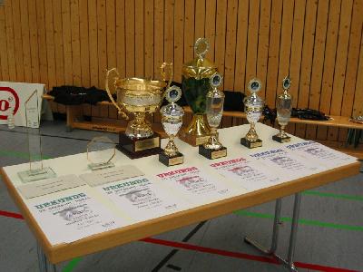 Die Pokale für die Sieger im Einzel. Links die Premium-Pokale mit der 24karätige Goldauflage. Im Hintergrund die Trophäen für die besten Mannschaften.